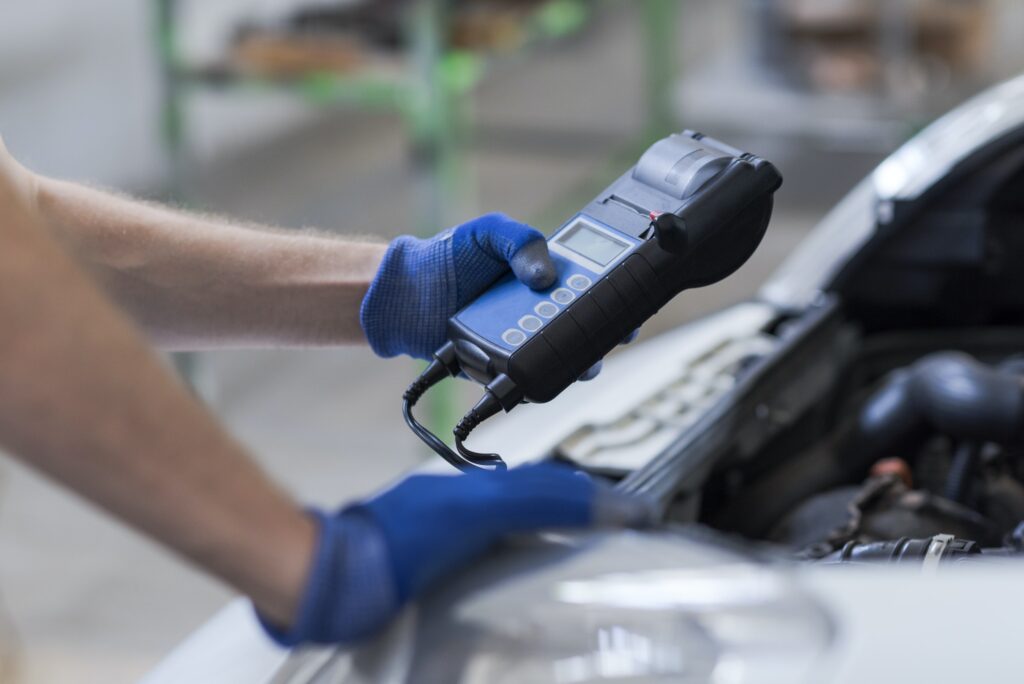 Mechanic using a battery tester